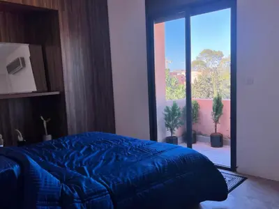 a bedroom with a blue bed and a large window at Appartement tout neuf à Gueliz Marrakech Plaza Zara in Marrakech