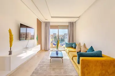 a living room with a yellow couch with blue pillows at New! Appt Moderne Jubaea avec parking & wifi in Marrakech