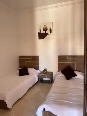 a room with two beds and a table at Abwab guilize Beautiful modern apartment in Marrakech