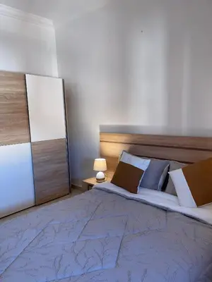 a bedroom with a large bed with a blue blanket and pillows at Abwab guilize Beautiful modern apartment in Marrakech