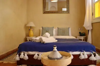a bedroom with a bed with blue sheets and a mirror at Riad Chez moi in Marrakech
