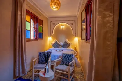 a bedroom with a bed with two chairs at Riad Le Graff Pink group in Marrakech
