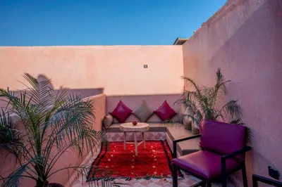 a patio with a table and a purple chair and plants at Riad Le Graff Pink group in Marrakech