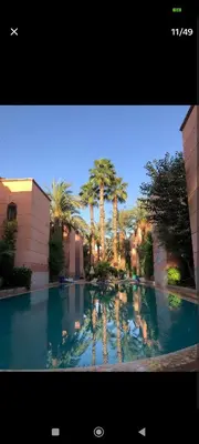 a large pool of water with palm trees and buildings at Riad Benhamou 3 in Marrakech
