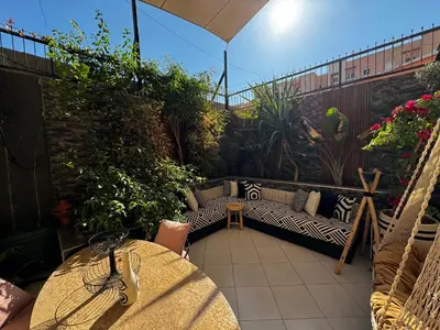 a patio with a couch and a table on a balcony at Duplexe super in Marrakech