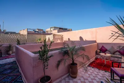 a rooftop patio with palm trees and a couch at Riad Le Graff Pink in Marrakech