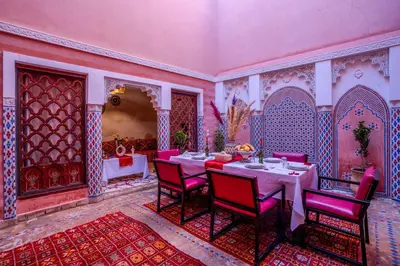 a dining room with a table and red chairs at Riad Le Graff Pink in Marrakech