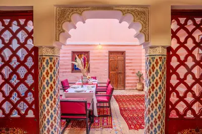 a dining room with a table and red chairs at Riad Le Graff Pink in Marrakech
