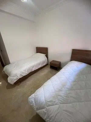 two beds in a white room with two tables at Cozy Apartment With Pool 5 min from Guéliz in Marrakech