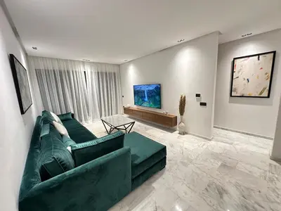 a living room with a green couch and a table at NEW LUXURY APARTMENT - ViCTOR HUGO MARRAKECH in Marrakech