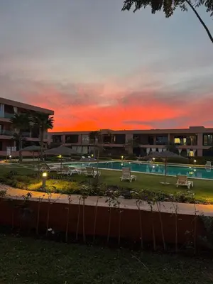 a resort with a swimming pool at sunset at Rez de Jardin T3 Piscine Noria in Marrakech