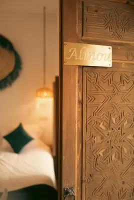 a wooden door with a sign on it next to a bed at Riad julines in Marrakech
