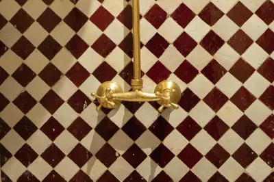 a gold toilet paper dispenser on a tiled wall at Riad julines in Marrakech