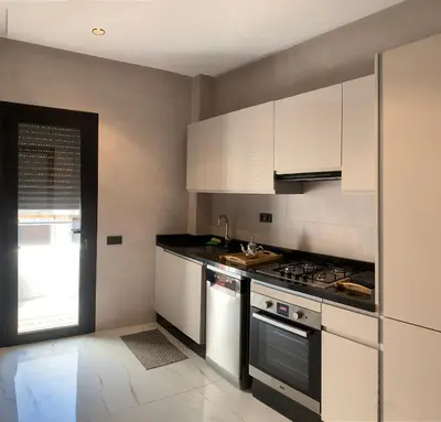 a kitchen with white cabinets and a stove at Appartement Mazal in Marrakech