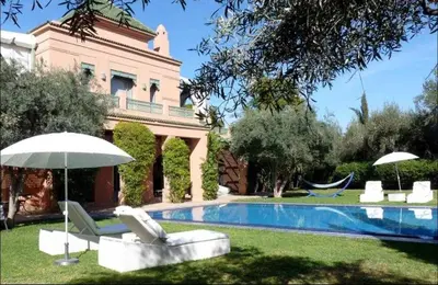 a house with a swimming pool with chairs and an umbrella at Luxury villa - AC- 5BR-11P- Palmeraie Marrakech in Marrakech