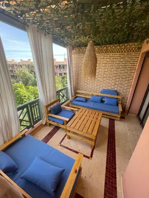 a balcony with blue couches and a table at Luxury 2BR with Pool & Garden View Balcony in Marrakech