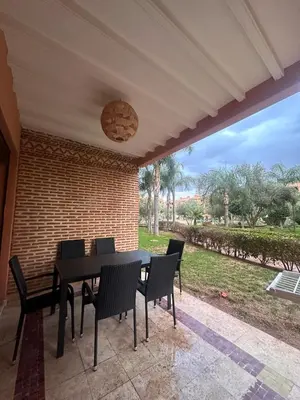 a patio with a table and chairs and a brick wall at Marrakech Oasis, Residence Ennaim 1 in Marrakech