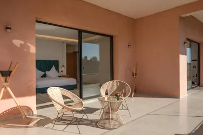 a room with two wicker chairs and a bedroom at La Salea - Golf Amelkis in Marrakech