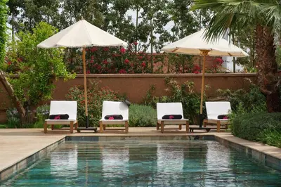 two chairs and umbrellas next to a swimming pool at Villa Ty Habibi - Super 5 Bedroom with Private Heated Pool by the Golf Amelkis in Marrakech