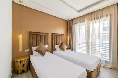 two beds in a room with a window at Cozy & Elegant appart in hypercenter of Marrakech in Marrakech