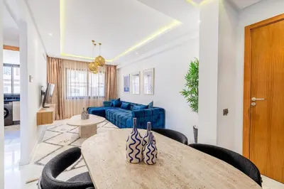 a living room with a table and a blue couch at Cozy & Elegant appart in hypercenter of Marrakech in Marrakech