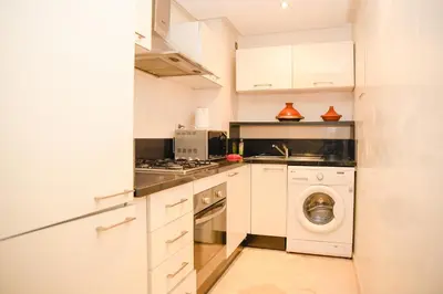 a kitchen with white cabinets and a washer and dryer at Chic & Modern in City Center - Pool, IPTV & Comfort in Marrakech