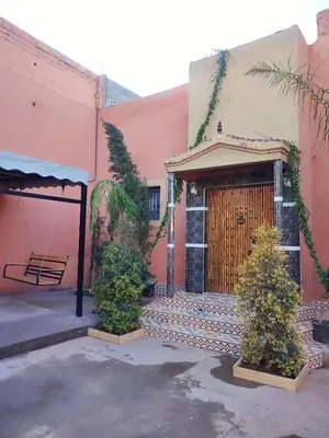 a pink building with a wooden door and a bench at Relaxing Family Home outside Marrakech in Marrakech
