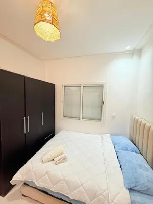 a bedroom with a large bed with a black cabinet at Appartement Tachfine lumineux FAMILY in Marrakech