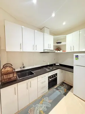 a kitchen with white cabinets and a sink at Appartement Tachfine lumineux FAMILY in Marrakech