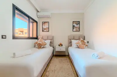two white beds in a room with two windows at New! Apartment Gueliz 2 min M Avenue with Pool and 24h Security & Parking in Marrakech