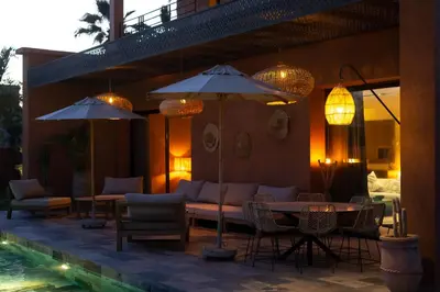 a patio with tables and chairs and umbrellas next to a pool at Villa luxe Dar Paumar, Marrakech in Marrakech
