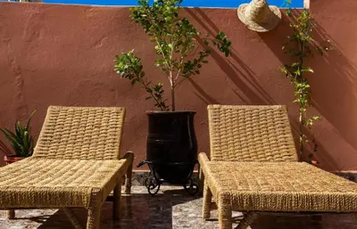 two wicker chairs sitting next to a wall with a grill at Terrace Room with Atlas View in Marrakech
