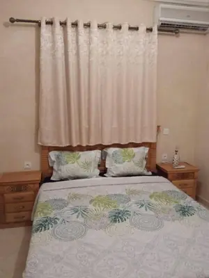 a bedroom with a bed with two pillows and a curtain at Joli appartement proche aéroport in Marrakech