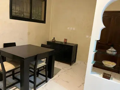 a dining room with a black table and chairs at Joli appartement proche aéroport in Marrakech