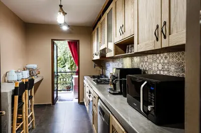 a kitchen with wooden cabinets and a black microwave at Zellige Suite - Gouvernante et piscine ! in Marrakech