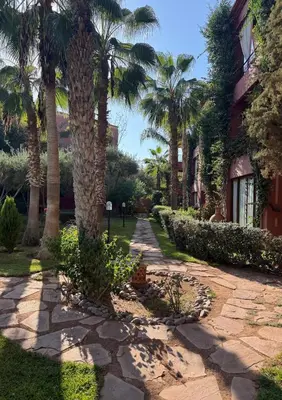 a walkway in front of a house with palm trees at Zellige Suite - Gouvernante et piscine ! in Marrakech