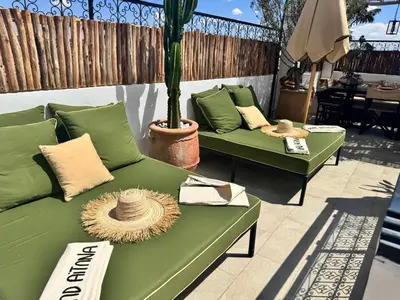 a patio with green couches and a palm tree at Riad de charme Aïtana au cœur de la Médina in Marrakech