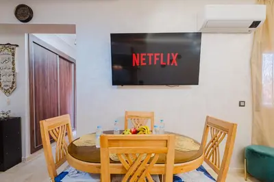 a table and chairs with a television on a wall at 1BR Appart 2 min de M Avenue , Pool , Balcony & Parking & 24h j7 security in Marrakech