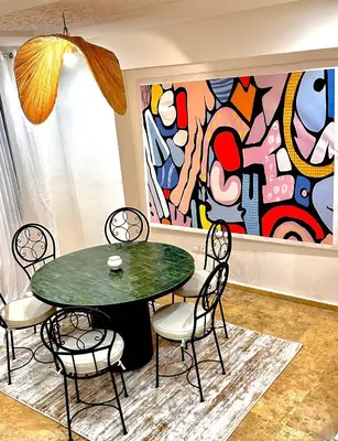 a table and chairs in a room with a painting at Les Paniers de MARRAKECH 1 in Marrakech