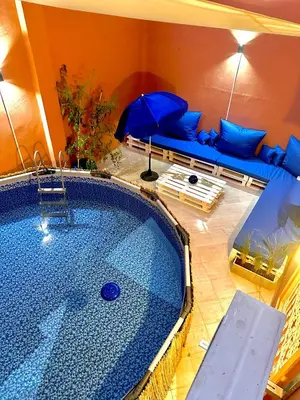 a large swimming pool with a couch and an umbrella at Les Paniers de MARRAKECH 1 in Marrakech