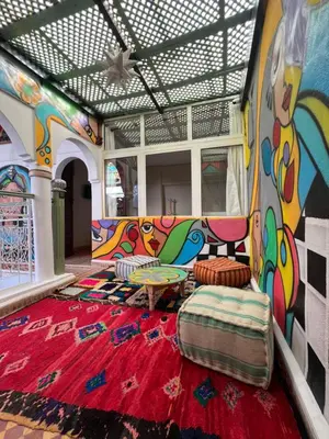 a living room with a red rug and a mural at Riad dar lfen in Marrakech