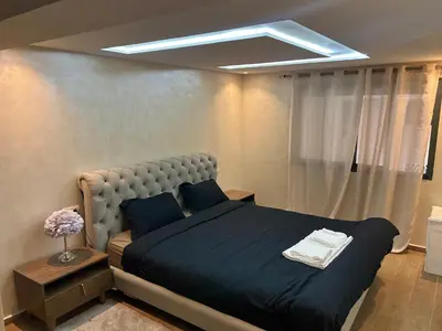 a bedroom with a large bed with a blue blanket at malak g7 in Marrakech