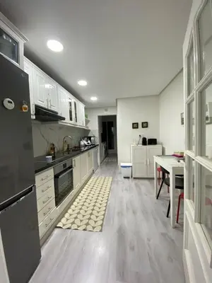 a large kitchen with white cabinets and a table at Appartement luxe in Marrakech