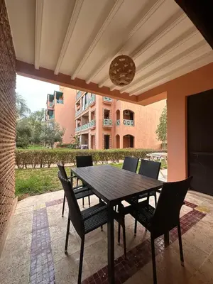 a wooden table and chairs on a patio at Marrakech Oasis, Residence Ennaim in Marrakech