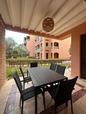 a wooden table and chairs on a patio at Marrakech Oasis, Residence Ennaim in Marrakech