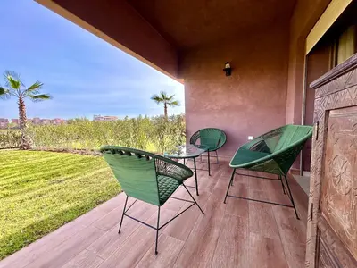 a patio with three chairs and a glass table on a porch at Appartement RDJ - Golf - Piscine - restaurants in Marrakech