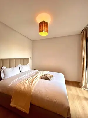 a bedroom with a large white bed and a lamp at Appartement RDJ - Golf - Piscine - restaurants in Marrakech