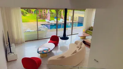 a living room with red and white furniture and a pool at villa du golf in Marrakech