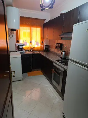 a kitchen with black cabinets and a white refrigerator at Magnifique appartement in Marrakech