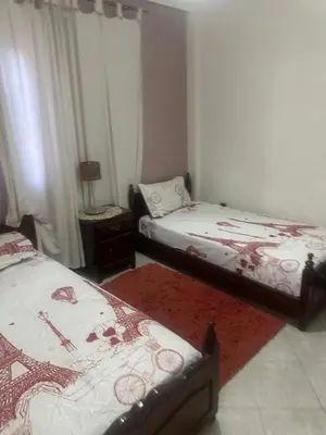 a bedroom with two beds and a red rug at Appartement Layane 2 chambres 8 mn de gueliz in Marrakech